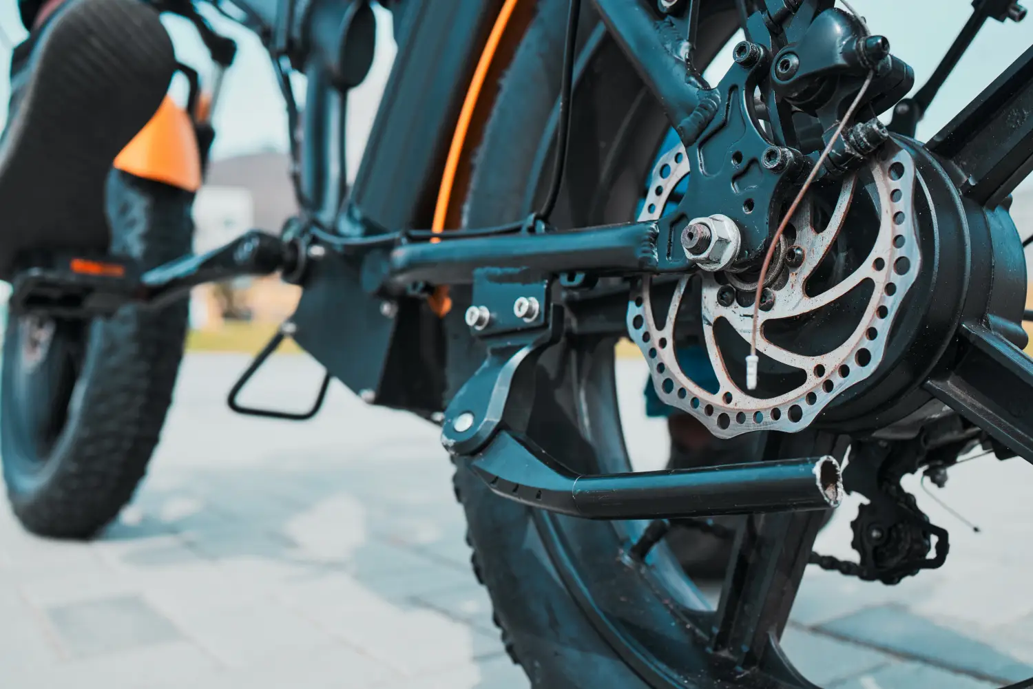 Zbliżenie na tylne koło elektrycznego roweru typu fatbike z widoczną tarczą hamulcową oraz silnikiem w piaście.